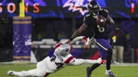 Baltimore Ravens quarterback Lamar Jackson (8) stiff arms New England Patriots linebacker K'Lavon Chaisson (44) during the first half of the game at M&T Bank Stadium.