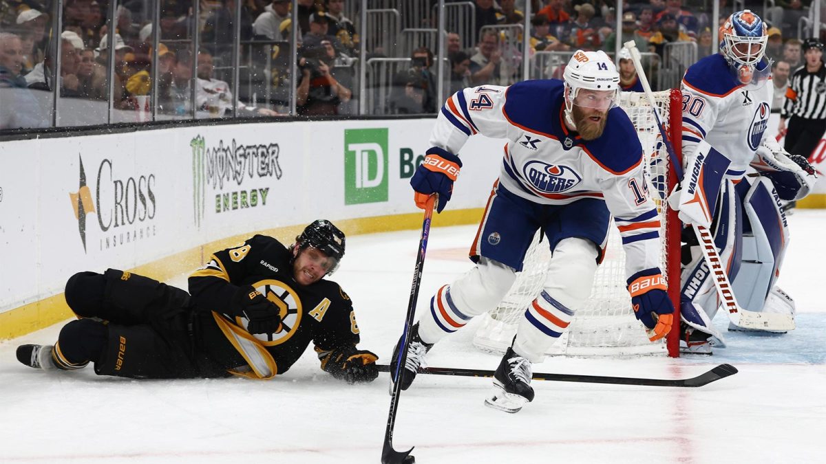 Edmonton Oilers defenseman Mattias Ekholm (14) skates the puck past fallen Boston Bruins right wing David Pastrnak (88) during the third period at TD Garden.