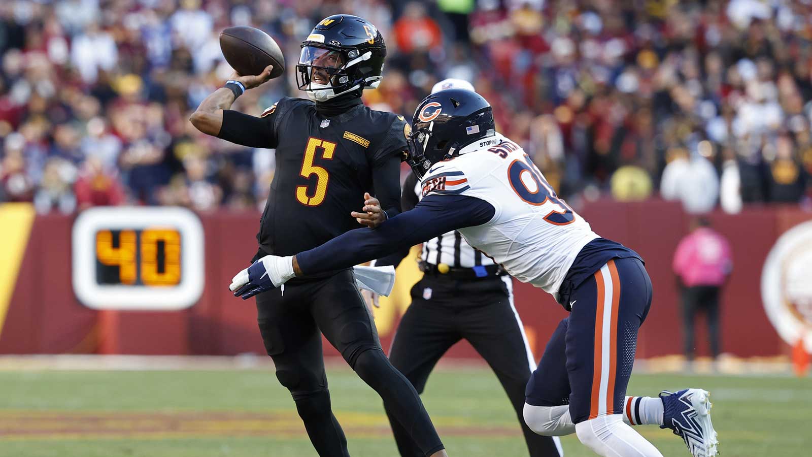 Washington Commanders quarterback Jayden Daniels (5) passes the ball as Chicago Bears defensive end Montez Sweat (98) chases during the first quarter at Northwest Stadium.
