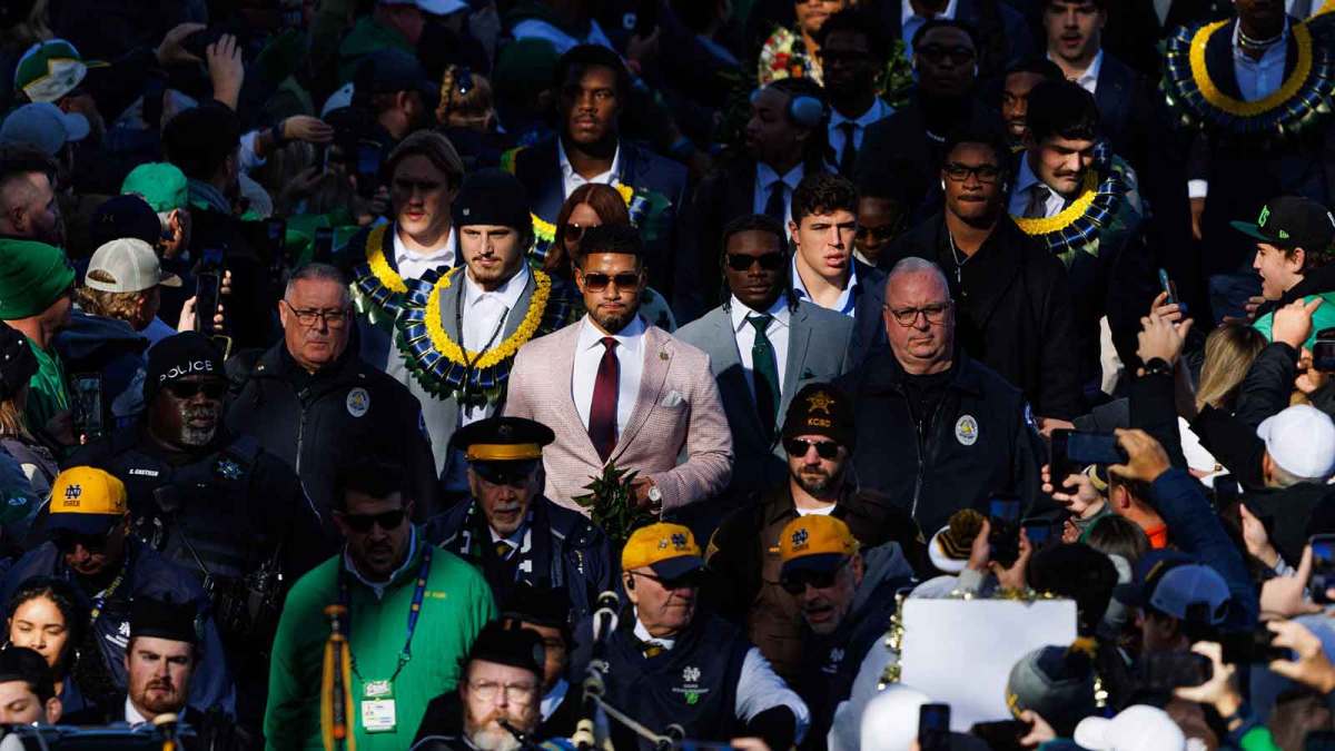 Notre Dame head coach Marcus Freeman, center, walks into Notre Dame Stadium with his players before a NCAA football game against Syracuse.