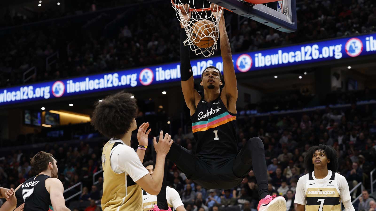 San Antonio Spurs forward Victor Wembanyama (1) dunks the ball as Washington Wizards forward Kyshawn George (18) and Wizards guard Bub Carrington (7) look on in the second quarter at Capital One Arena.