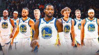 A close up of the Warriors' Jonathan Kuminga looking sad and off into the distance, with Steve Kerr, Steph Curry, Jimmy Butler, Draymond Green on the left-side of him and Brandin Podziemski, Pat Spencer, and Moses Moody on the other side of him