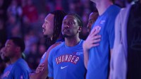 Thunder guard Jalen Williams (8) stands with teammates during the singing of the national anthem before a game against the Portland Trail Blazers at Moda Center with the Warriors logo in the background