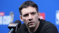 Thunder head coach Mark Daigneault at press conference prior to the Emirates Cup semifinals at T-Mobile Arena with Spurs Victor Wembanyama in the background