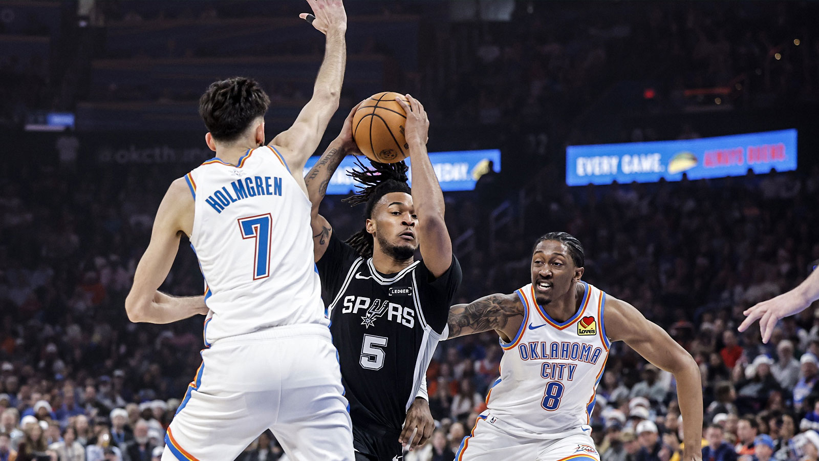 Spurs guard Stephon Castle (5) drives between Oklahoma City Thunder guard Jalen Williams (8) and center Chet Holmgren (7) during the first quarter at Paycom Center
