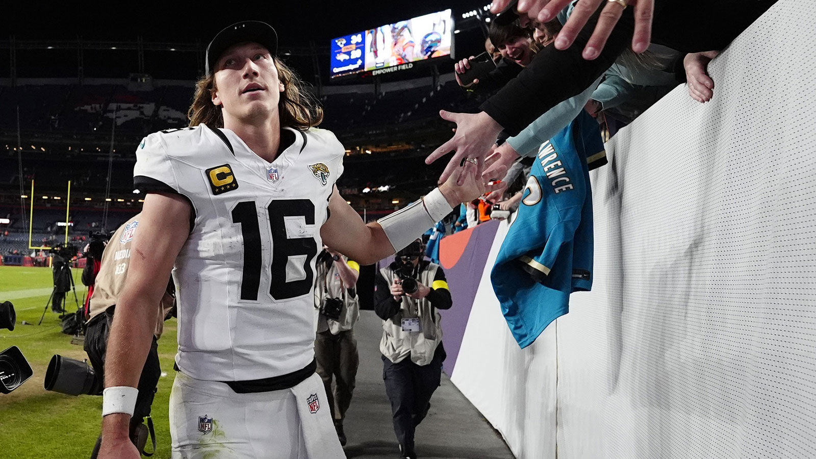 Jacksonville Jaguars quarterback Trevor Lawrence (16) shakes hands with fans after the game at Empower Field at Mile High. 