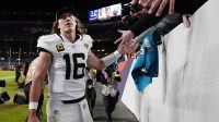 Jacksonville Jaguars quarterback Trevor Lawrence (16) shakes hands with fans after the game at Empower Field at Mile High.