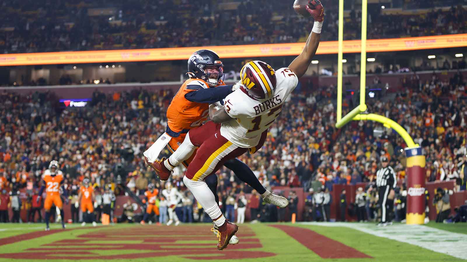 Washington Commanders wide receiver Treylon Burks (13) makes a catch for a touchdown defended by Denver Broncos cornerback Riley Moss (21) in the third quarter of the game at Northwest Stadium. 