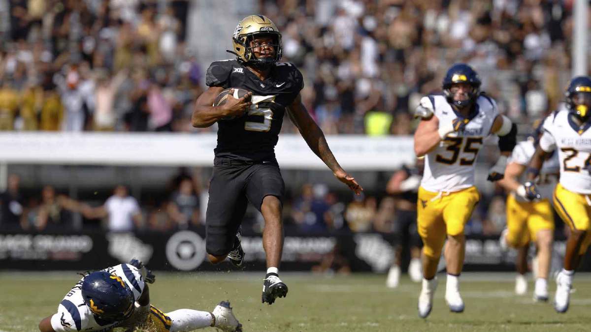 Central Florida Knights running back Jaden Nixon (5) runs for an 83 yard touchdown after slipping past the diving tackle attempt by West Virginia Mountaineers saftey Derek Carter Jr. (13) in the second half at Acrisure Bounce House.