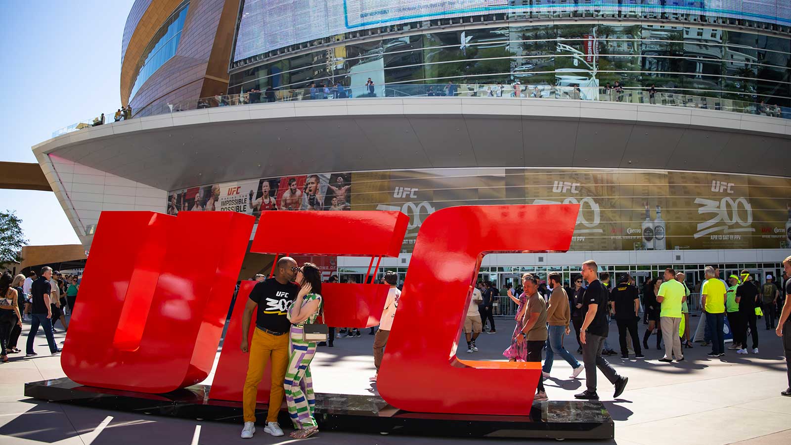 A couple kisses in front of a UFC logo prior to UFC 300 at T-Mobile Arena.