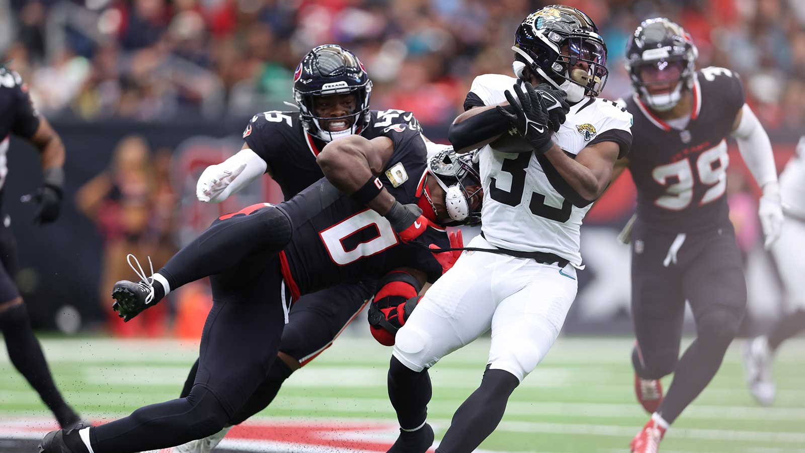 Jacksonville Jaguars running back Bhayshul Tuten (33) is tackled by Houston Texans linebacker Azeez Al-Shaair (0) during the first half at NRG Stadium.