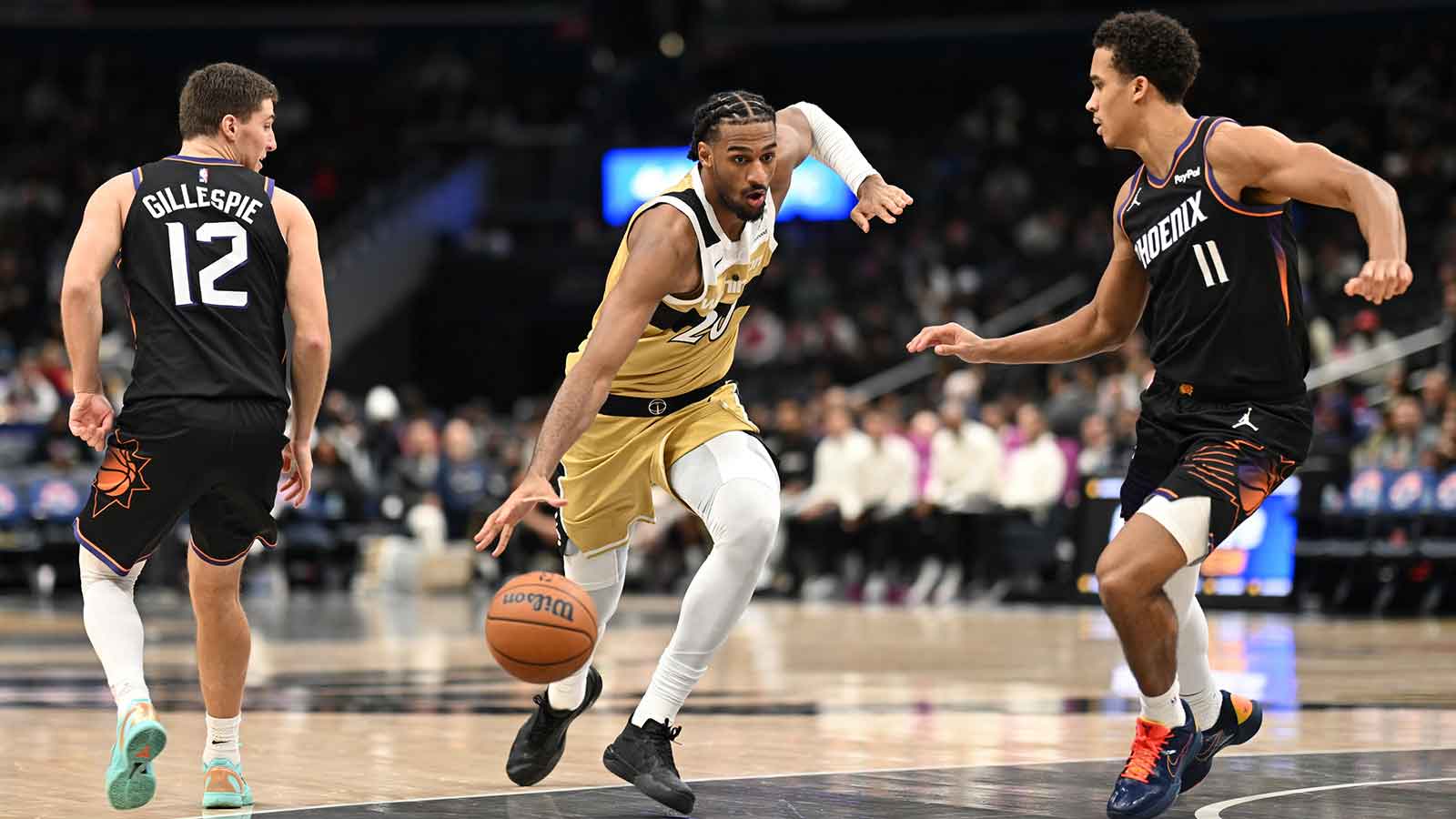 Washington Wizards center Alex Sarr (20) dribbles the ball between Phoenix Suns guard Collin Gillespie (12) and forward Oso Ighodaro (11) during the third quarter at Capital One Arena.
