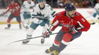 Washington Capitals left wing Alex Ovechkin (8) and San Jose Sharks defenseman Sam Dickinson (6) chase the puck during the third period at Capital One Arena.