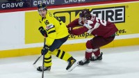 Sweden forward Anton Frondell (16) skates with the puck as Latvia forward Antons Macijevskis (22) defends during the third period in the quarterfinals of the 2026 IIHF World Junior Championship at Grand Casino Arena.
