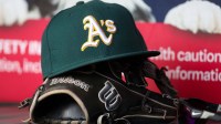 A detailed view of an Oakland Athletics hat and glove on the field against the Atlanta Braves in the sixth inning at Truist Park.