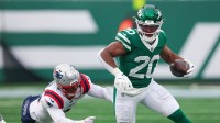 New York Jets running back Breece Hall (20) carries the ball as New England Patriots linebacker K'Lavon Chaisson (44) pursues at MetLife Stadium.