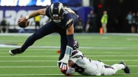 Los Angeles Chargers quarterback Justin Herbert (10) is tripped up by Houston Texans safety K'Von Wallace (38) during the second half at SoFi Stadium