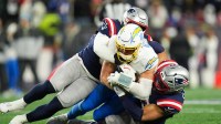 Jan 11, 2026; Foxborough, MA, USA; Los Angeles Chargers quarterback Justin Herbert (10) is tackled by New England Patriots linebacker Elijah Ponder (91) during the fourth quarter in an AFC Wild Card Round game at Gillette Stadium. Mandatory Credit: David Butler II-Imagn Images
