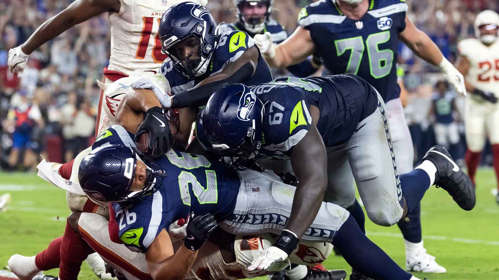 Seattle Seahawks running back Zach Charbonnet (26) is pushed across the goal line by tackle Charles Cross (67) to score a touchdown against Arizona Cardinals safety Jalen Thompson (34) in the second quarter at State Farm Stadium.