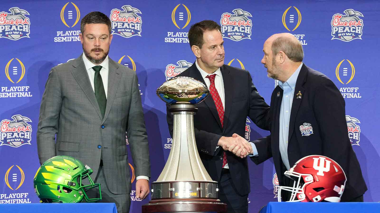 Oregon Ducks head coach Dan Lanning and Indiana Hoosiers head coach Curt Cignetti shake hands with Gary Stokan on Thursday, Jan. 8, 2026, during a coaches' press conference ahead of the College Football Playoff Peach Bowl game at the College Football Hall of Fame in Atlanta.