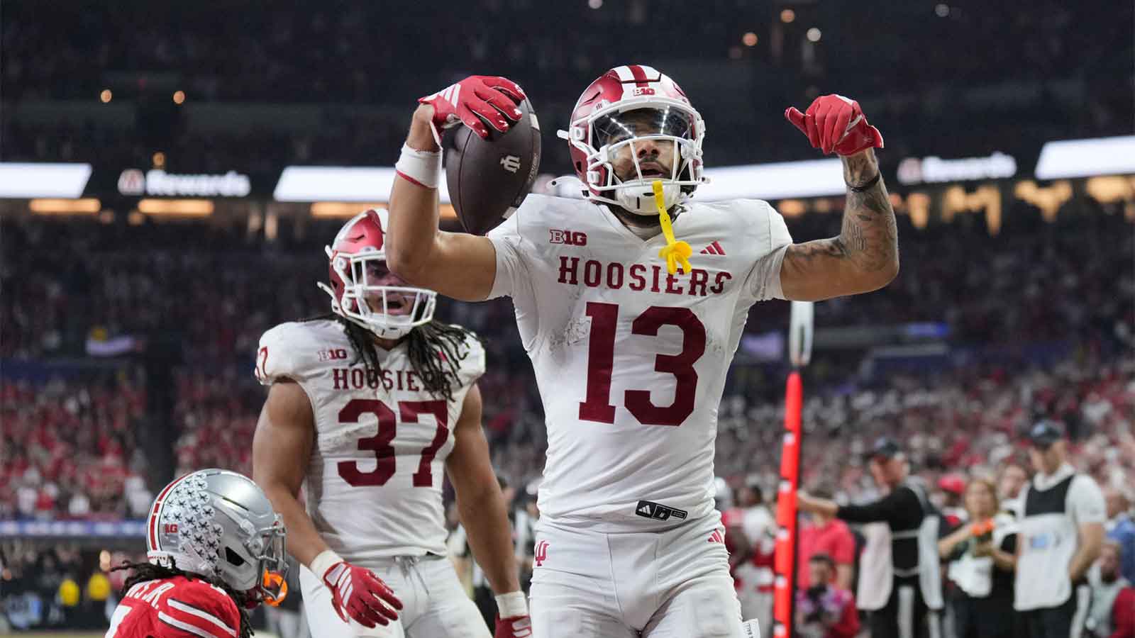 Indiana Hoosiers wide receiver Elijah Sarratt (13) celebrates after scoring a touchdown against Ohio State Buckeyes cornerback Jermaine Mathews Jr. (7) in the third quarter during the 2025 Big Ten championship game at Lucas Oil Stadium.