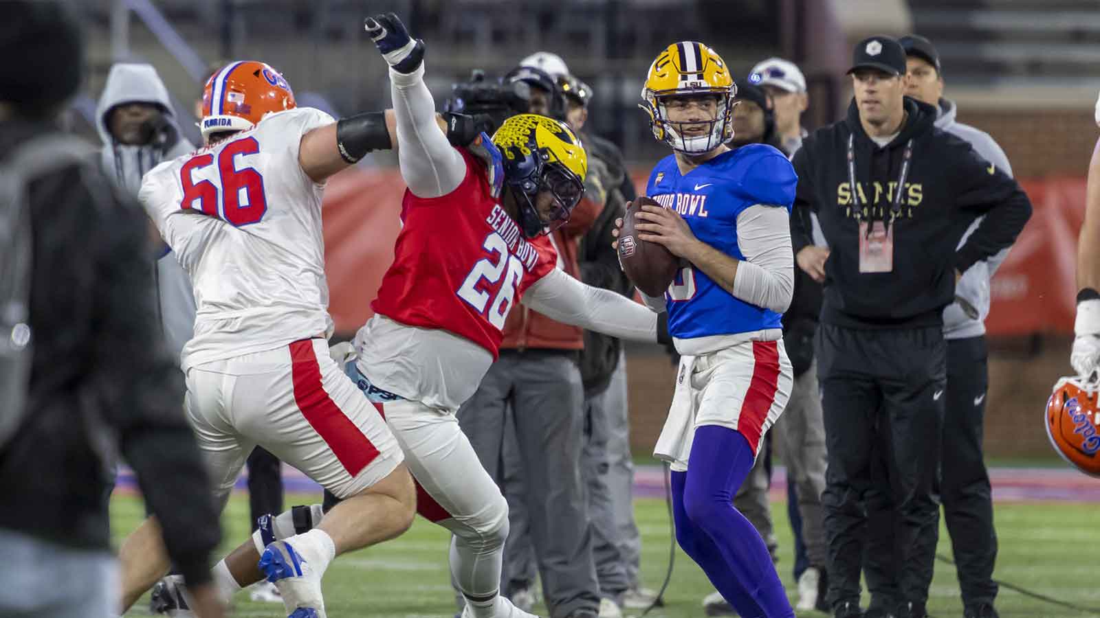 American Team defensive tackle Rayshaun Benny (26) of Michigan battles American Team offensive lineman Jake Slaughter (66) of Florida to get to American Team quarterback Garrett Nussmeier (13) during American Senior Bowl practice at Hancock Whitney Stadium.