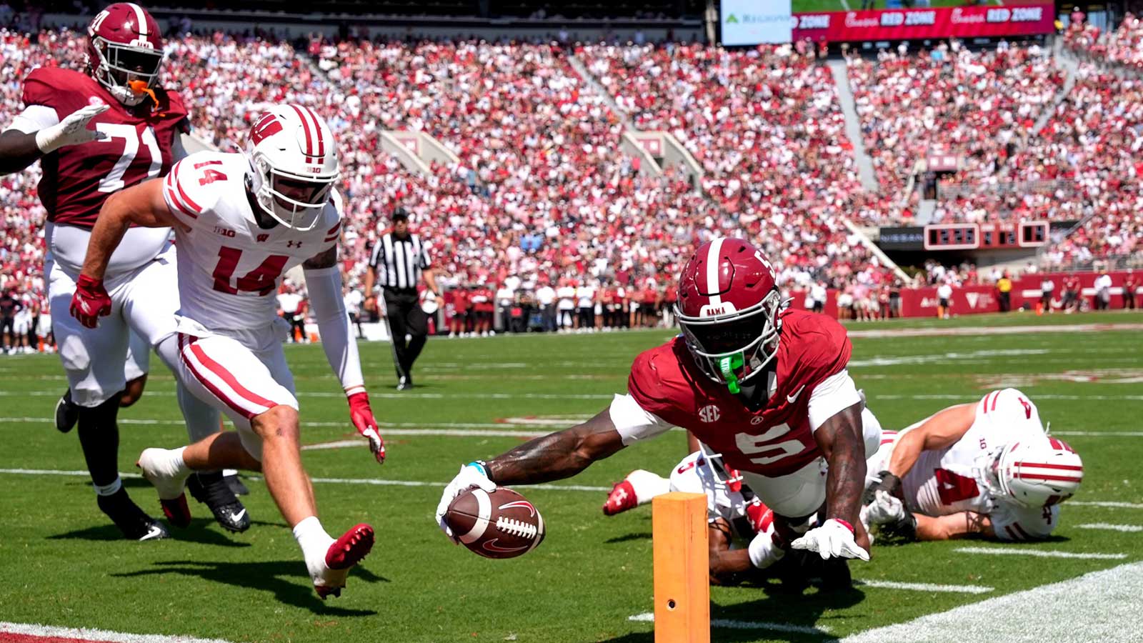 Alabama wide receiver Germie Bernard (5) dives for a score at the pylon with Wisconsin defensive back Preston Zachman (14), Wisconsin defensive back D'Yoni Hill (5) and Wisconsin linebacker Tackett Curtis (4) unable to make the stop at Saban Field at Bryant-Denny Stadium.