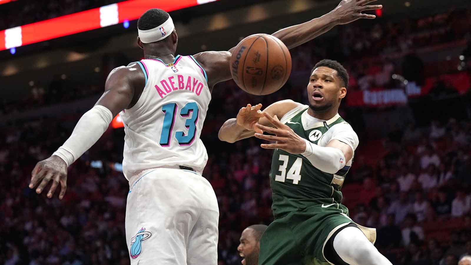 Milwaukee Bucks forward Giannis Antetokounmpo (34) passes the ball under the arm of Miami Heat center Bam Adebayo (13) during overtime at Kaseya Center.