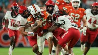 Miami Hurricanes running back Girard Pringle Jr. (22) carries the football against NC State Wolfpack defensive end Travali Price (13) and defensive back Ronnie Royal (2) during the fourth quarter at Hard Rock Stadium.