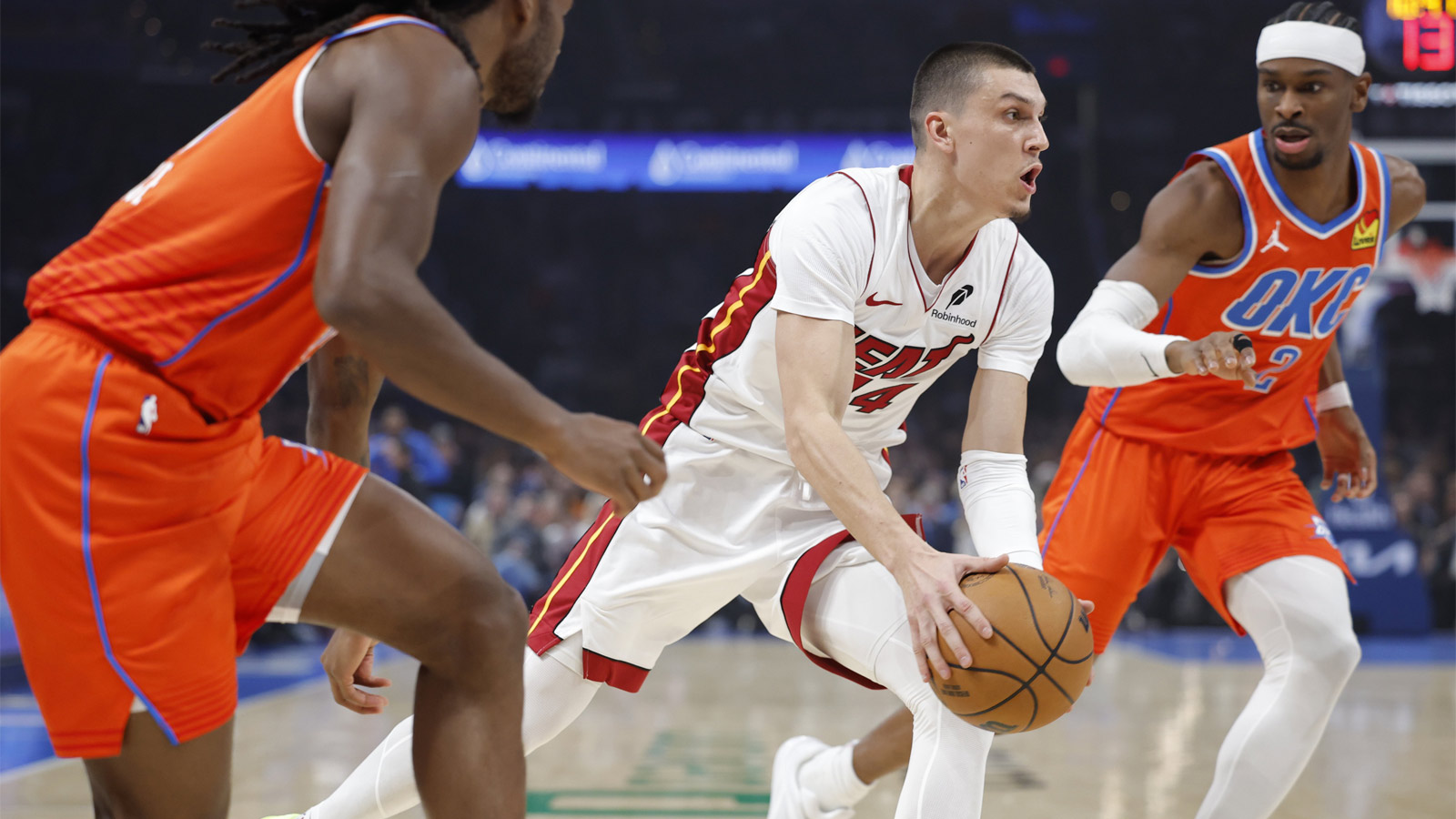 Heat guard Tyler Herro (14) drives between Oklahoma City Thunder guard Cason Wallace (22) and guard Shai Gilgeous-Alexander (2) during the first quarter at Paycom Center