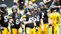 Iowa offensive linemen Trevor Lauck (59) Leighton Jones (64) Logan Jones (65) Kade Pieper (58) and Gennings Dunker (67) huddle up with quarterback Hank Brown (9) during the Hawkeyes Kids Day NCAA football open practice at Kinnick Stadium in Iowa City, Iowa.