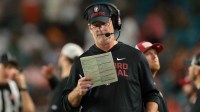 Stanford Cardinal interim head coach Frank Reich reads a play card against the Miami Hurricanes during the third quarter at Hard Rock Stadium.