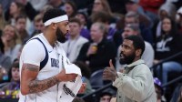 Mavericks forward Anthony Davis (l3) and guard Kyrie Irving (right) speak during a second half break in action against the Utah Jazz at Delta Center with ESPN's Kendrick Perkins in the background
