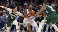 Memphis Grizzlies guard Ja Morant (12) handles the ball as Milwaukee Bucks guard Ryan Rollins (13) and forward Kyle Kuzma (18) defend during the fourth quarter at FedExForum.
