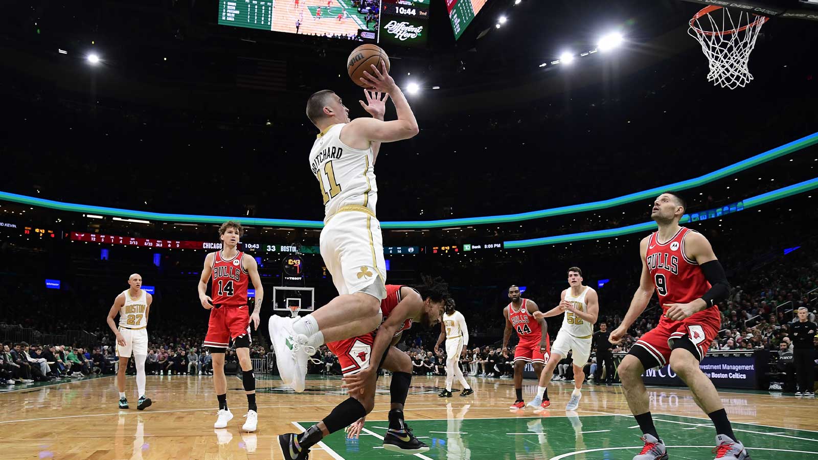 Boston Celtics guard Payton Pritchard (11) shoots the ball while Chicago Bulls center Nikola Vucevic (9) looks on during the first half at TD Garden.