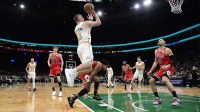 Boston Celtics guard Payton Pritchard (11) shoots the ball while Chicago Bulls center Nikola Vucevic (9) looks on during the first half at TD Garden.