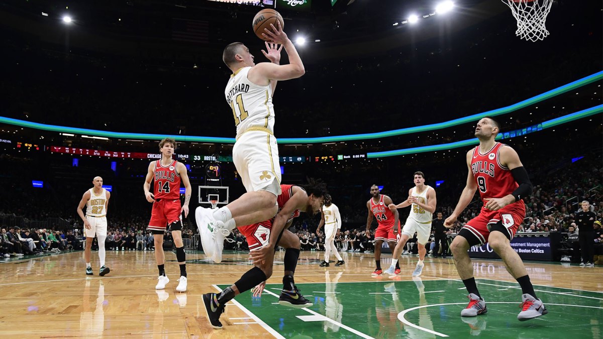 Boston Celtics guard Payton Pritchard (11) shoots the ball while Chicago Bulls center Nikola Vucevic (9) looks on during the first half at TD Garden.