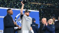Seattle Seahawks quarterback Sam Darnold (14) celebrates with the trophy on the podium after defeating the Los Angeles Rams in the 2026 NFC Championship Game at Lumen Field.