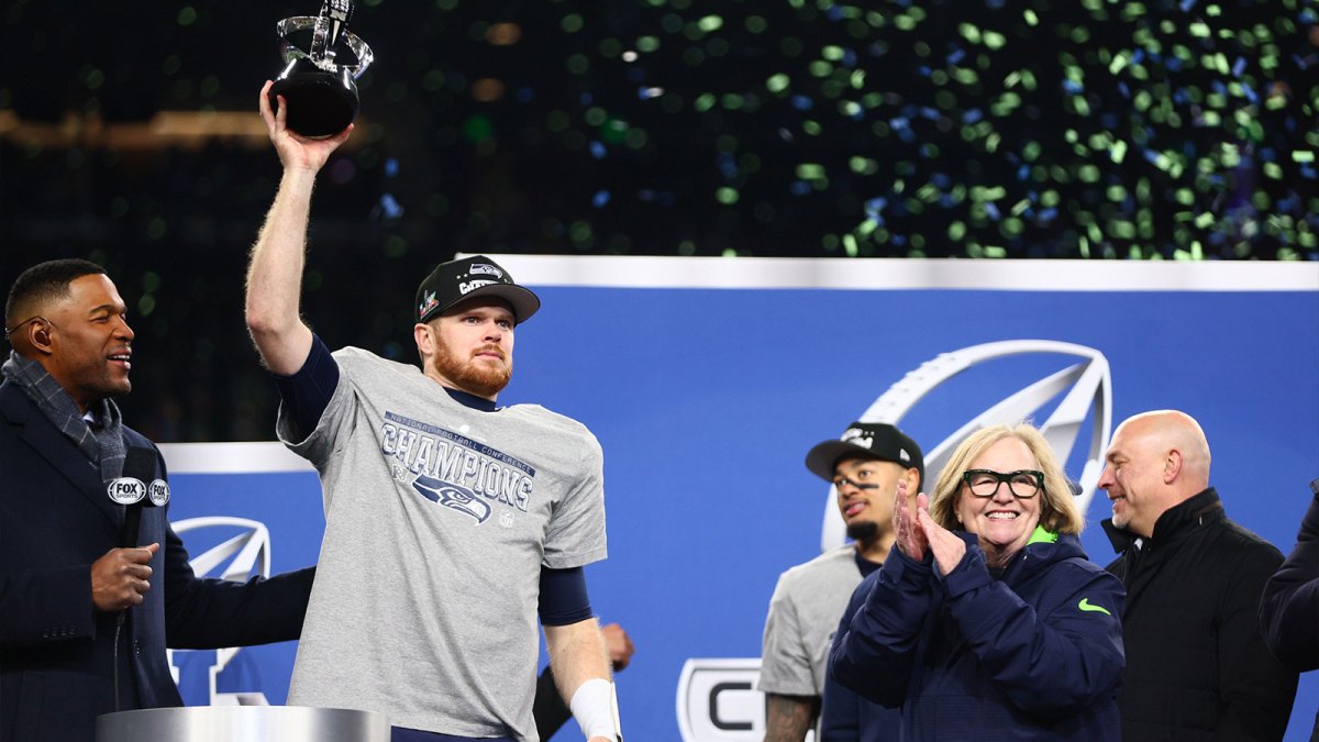 Seattle Seahawks quarterback Sam Darnold (14) celebrates with the trophy on the podium after defeating the Los Angeles Rams in the 2026 NFC Championship Game at Lumen Field.