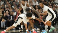 San Antonio Spurs guards Dylan Harper (2) and Stephon Castle (5) battle for the loose ball with Miami Heat guard Davion Mitchell (45) during the first half at Frost Bank Center.