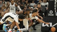 San Antonio Spurs guards Dylan Harper (2) and Stephon Castle (5) battle for the loose ball with Miami Heat guard Davion Mitchell (45) during the first half at Frost Bank Center.