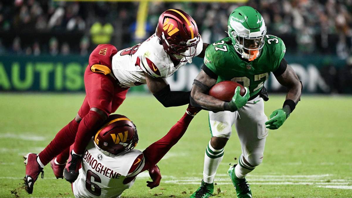 Philadelphia Eagles running back Tank Bigsby (37) rushes and is tackled by Washington Commanders cornerback Noah Igbinoghene (6) and Washington Commanders safety Jeremy Reaves (39) during the fourth quarter at Lincoln Financial Field.