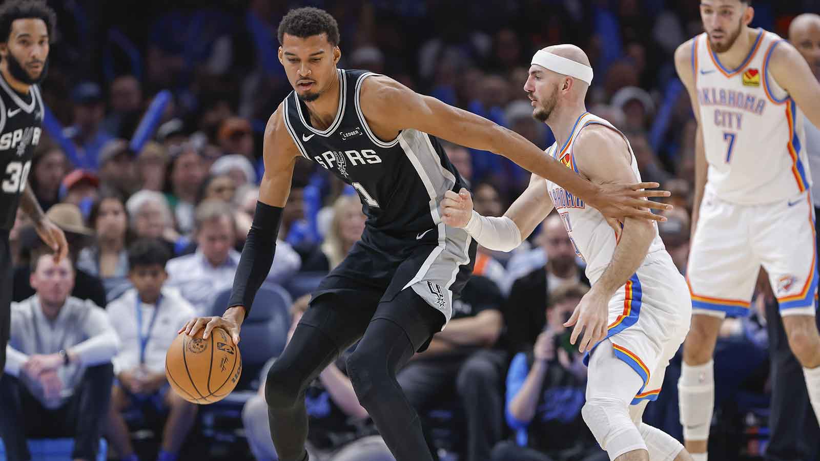 Spurs forward Victor Wembanyama (1) moves the ball across the court against Oklahoma City Thunder guard Alex Caruso (9) during the second half at Paycom Center