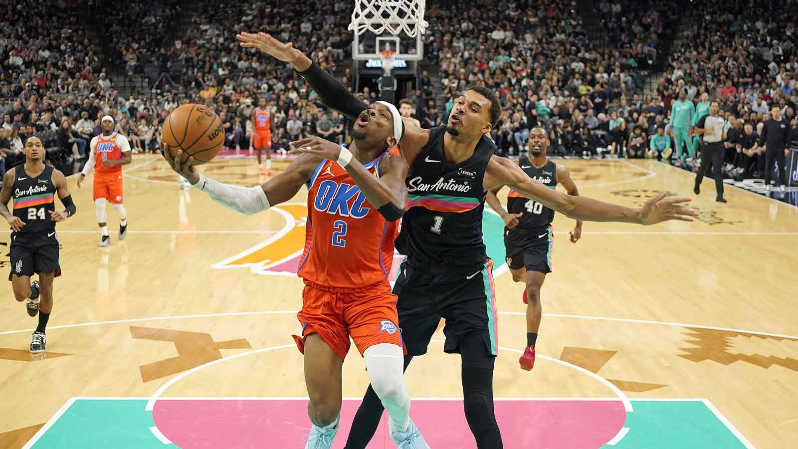 Thunder guard Shai Gilgeous-Alexander (2) drives to the basket past San Antonio Spurs forward Victor Wembanyama (1) during the first half at Frost Bank Center
