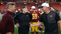 (L-R) Washington Commanders general manager Adam Peters, Commanders head coach Dan Quinn, and Cincinnati Bengals head coach Zac Taylor talk on the field after their game at Northwest Stadium.