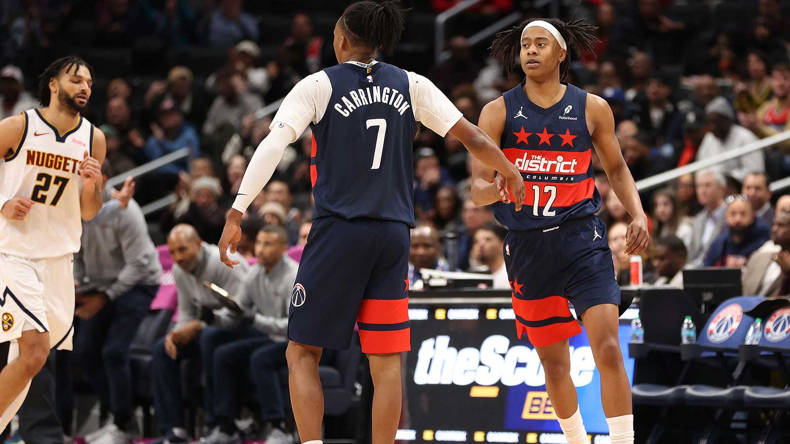 Washington Wizards guard Tre Johnson (12) celebrates with guard Bub Carrington (7) during the second half against the Denver Nuggets at Capital One Arena.