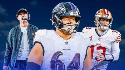 Tyler Linderbaum in the middle, Brock Purdy and coach Kyle Shanahan around him, Blue skies in the background