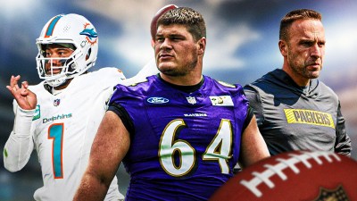 Tyler Linderbaum in the middle, Tua Tagovailoa and coach Jeff Hafley around him, Blue skies in the background