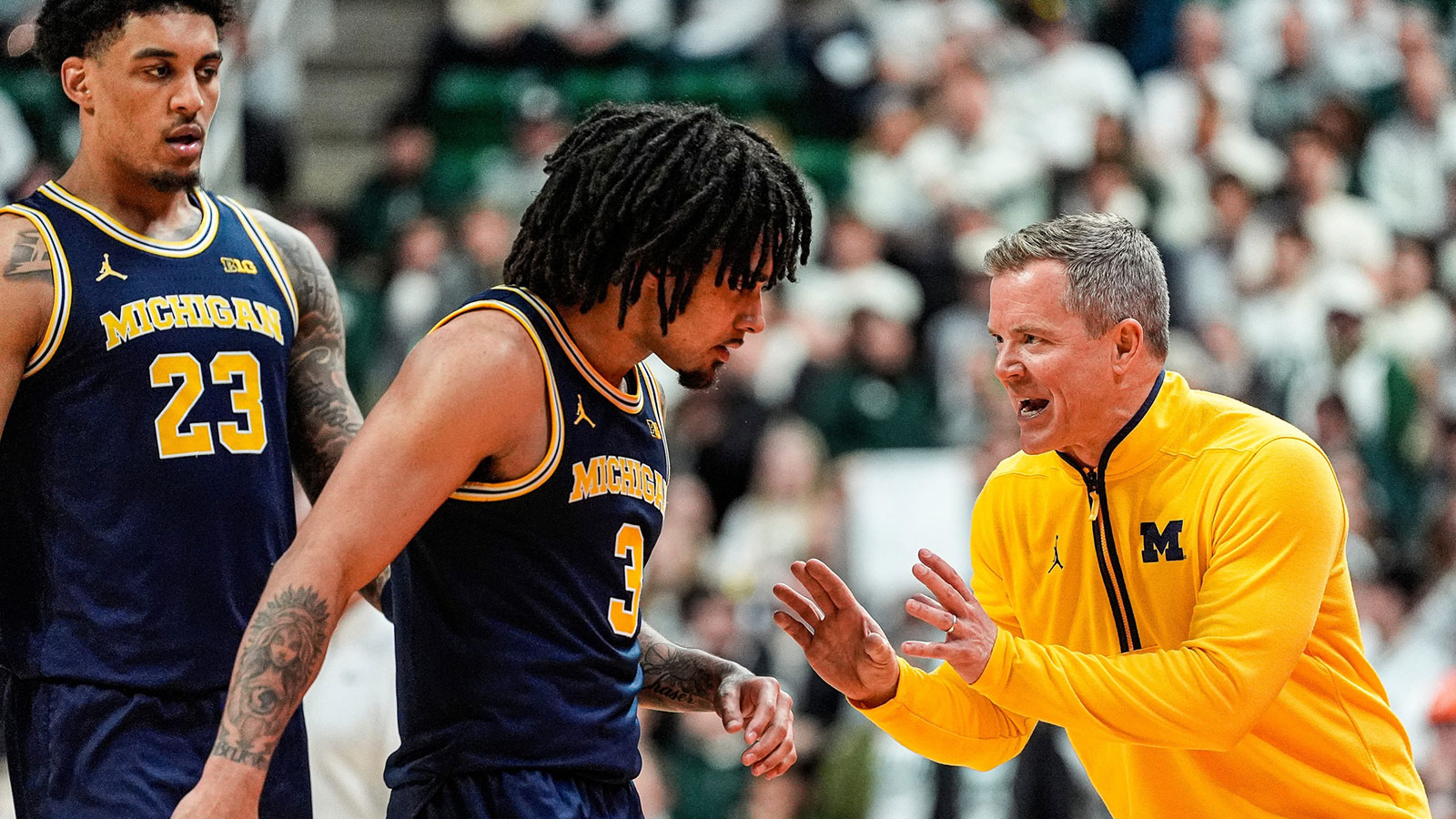 Michigan head coach Dusty May, right, talks to guard Elliot Cadeau (3), and forward Yaxel Lendeborg (23) before a play against Michigan State during the second half at Breslin Center in East Lansing on Friday, Jan. 30, 2026.