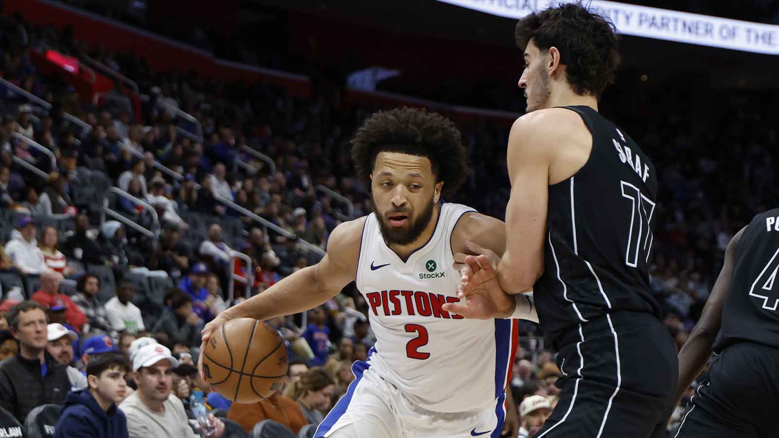 Detroit Pistons guard Cade Cunningham (2) dribbles defended by Brooklyn Nets guard Ben Saraf (77) in the second half at Little Caesars Arena.